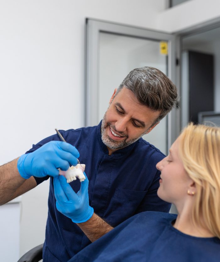 Dentist showing dental plaster mold to the patient. Dentist doctor showing jaw model at dental clinic, dental care concept. Dental care concept.