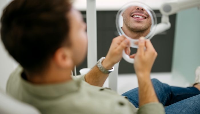 Male patient looks at himself in the mirror at the dentist