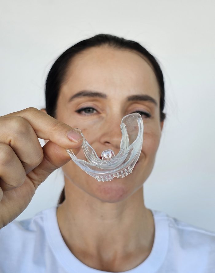 Woman holding transparent dental mouth guard on white background. Health and correct bite of teeth