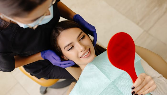 Girl is sitting in a dental chair in a dentist's office. The dentist checks the patient's condition by touching her head.