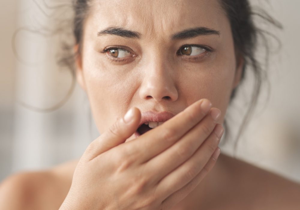 Woman is checking smell of breath