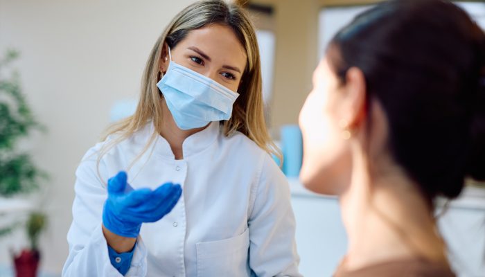 Female doctor in a medical uniform and protective face mask consulting with a patient in a clinic or hospital