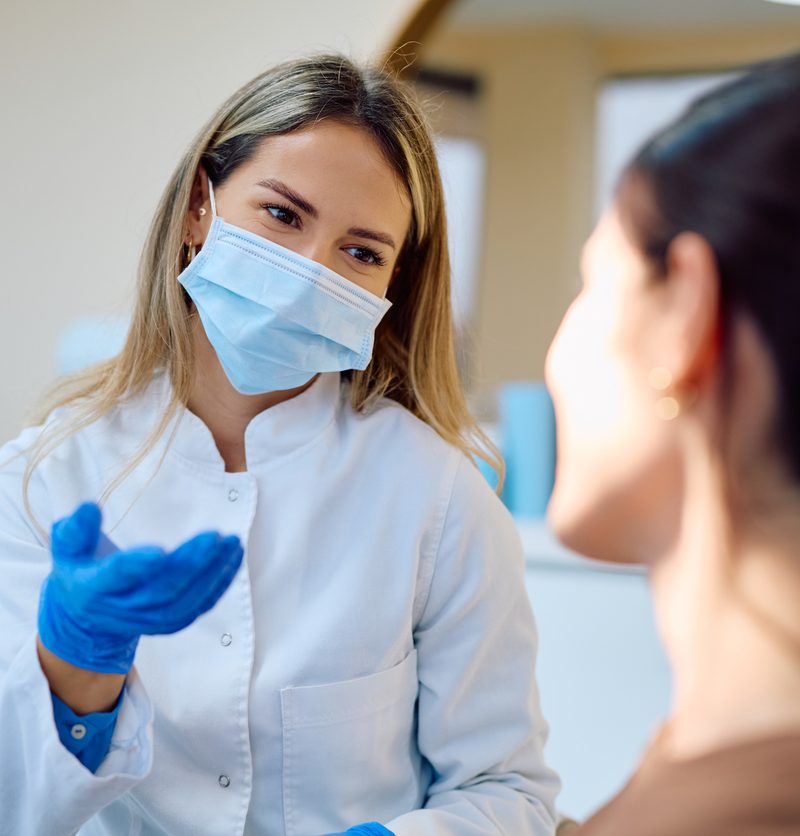 Female doctor in a medical uniform and protective face mask consulting with a patient in a clinic or hospital